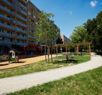Spielplatz mit Wohngebäude im Stadtteil Juh von Košice, umgeben von Grünflächen und einem Gehweg.