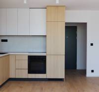 Küche in einer 2-Zimmer-Wohnung mit Holzschränken und schwarzen Geräten.