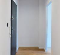 Flur mit Holzboden, weißen Wänden und Türen in einer Zweizimmerwohnung.