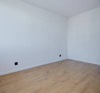 Ein leerer Raum mit weißen Wänden und Holzboden in einer Zweizimmerwohnung.