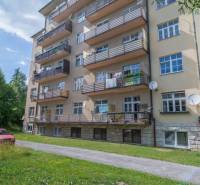 Ein fünfstöckiges Wohnhaus in der Hohen Tatra mit Balkonen und einem grünen Rasen.
