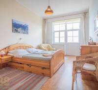Helles Schlafzimmer mit Holzmöbeln und einem Korbsessel in einer 3-Zimmer-Wohnung.