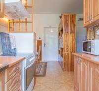 Küche in einer 3-Zimmer-Wohnung mit Herd, Mikrowelle und Holzschränken.