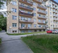 Ein Wohnhaus in der Hohen Tatra mit Balkonen und einem Parkplatz vor dem Gebäude.