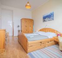 Schlafzimmer mit Holzmöbeln, einem Bild von Bergen und Korbdekorationen in einer 3-Zimmer-Wohnung.
