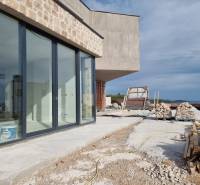 Der Bau einer Villa in Vodice mit einer verglasten Wand und einer Baustelle an der Küste.