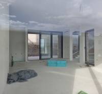 Geräumiges Interieur einer Villa mit großen Fenstern und Blick auf das Äußere.