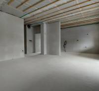 Innenraum eines Einfamilienhauses mit nackten Wänden, Vorbereitung für Installationen und großen Fenstern.