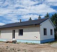 Ein Einfamilienhaus in Kozárovce mit einem dunklen Dach, umgeben von Grünflächen und Baumaterialien.