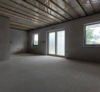 Innenraum eines Einfamilienhauses mit unvollendeten Wänden und Blick auf Fenster und Terrasse.