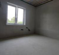 Ein leerer Raum in einem Einfamilienhaus mit einem Kunststofffenster und einer unfertigen Decke.