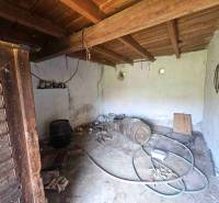 Innenraum eines Familienhauses mit einem Holzfass, alten Werkzeugen und einem Schlauch auf dem Boden.