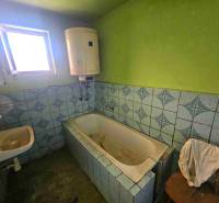 Badezimmer mit Badewanne und Waschbecken in einem Einfamilienhaus mit blauen Fliesen.