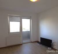 Ein Zimmer in einer Einzimmerwohnung mit Balkon, Holzboden, Fernseher an der Wand.