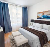 Schlafzimmer mit Bett, dunkelblauen Vorhängen und einem Bild in einer 2-Zimmer-Wohnung.