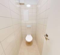 Badezimmertür in einer 2-Zimmer-Wohnung mit weißer Toilette und hellen Fliesen.