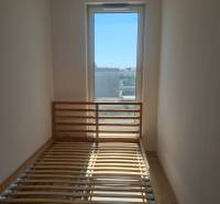 Helles Zimmer in einer Einzimmerwohnung mit Bett und großem Fenster.