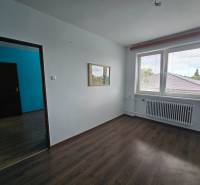Ein leerer Raum mit Laminatboden in einem Einfamilienhaus, mit einem großen Fenster und einem Heizkörper.