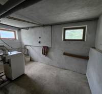 Heizraum in einem Einfamilienhaus mit Kessel, Rohrleitungen und kleinen Fenstern.