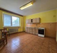 Eine Küche in einem Einfamilienhaus mit gelben Wänden, Holzmöbeln und Keramikfliesen.