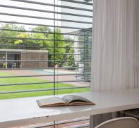 Innenraum eines Einfamilienhauses mit Blick auf den Garten und den Pool durch horizontale Jalousien.