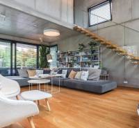 Ein stilvolles Wohnzimmer mit Holzboden, Treppe und großen Fenstern in einem Einfamilienhaus.