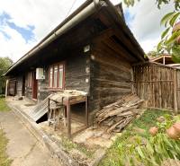 Holzhütte in Papradno mit einem Holzvorrat und Obstbäumen im Hof.