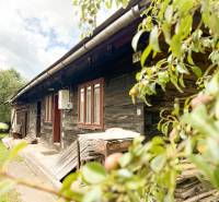 Eine Holzhütte in Papradno, umgeben von Natur, mit ländlicher Atmosphäre und grünem Rasen.