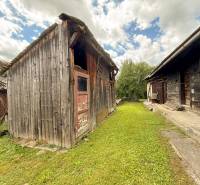 Holzgebäude bei der Hütte in Papradno, umgeben von Grün und blauem Himmel.