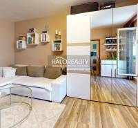 Wohnzimmer in einer 2-Zimmer-Wohnung mit einem weißen Sofa und einem Spiegelschrank.
