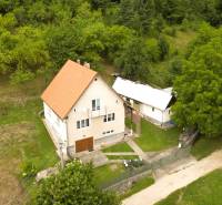 Ein Einfamilienhaus in Papradno, umgeben von einem grasbewachsenen Grundstück und Bäumen, mit einer Zufahrtsstraße.