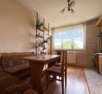 Ein Einfamilienhaus mit einer Küche, die Holzmöbel, einen Esstisch und ein Regal mit Dekorationen enthält.