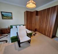 Schlafzimmer in einem Einfamilienhaus mit Bett, Sessel, großem Schrank und Bild an der Wand.