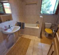 Badezimmer in einem Einfamilienhaus mit beleuchtetem Fenster, Badewanne und Waschbecken.