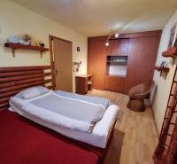Schlafzimmer eines Einfamilienhauses mit Bett, Schrank und Rattanstuhl.