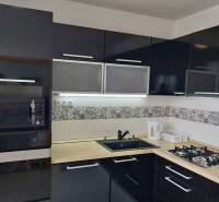 Küche in einer 3-Zimmer-Wohnung mit schwarzen Schränken, eingebautem Ofen und Gasherd.
