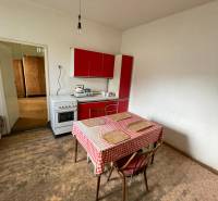 Eine Küche in einem Einfamilienhaus mit einem Esstisch und einer roten Küchenzeile.