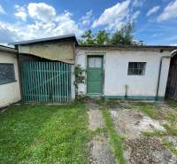 Ein Einfamilienhaus in Trenčianske Stankovce mit grüner Tür, kleinem Fenster und Rasen.