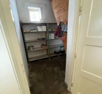 Speisekammer in einem Einfamilienhaus mit Regalen, offenem Fenster und Holzverkleidung an der Wand.