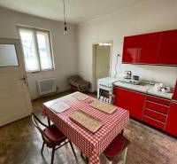 Eine Küche in einem Einfamilienhaus mit einer roten Küchenzeile und einem Esstisch.