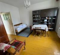 Innenraum eines Einfamilienhauses mit Esstisch, Bett und Vitrine.