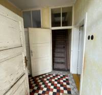 Eingangsflur in einem Einfamilienhaus mit kariertem Boden und Holztreppe.