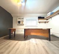 Ein Büro mit Schreibtisch und Regalen in einer 4-Zimmer-Wohnung, heller Boden, minimalistisches Design.