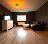 Wohnzimmer in einer Vierzimmerwohnung mit schwarzem Sofa und weißer Kommode.