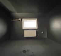 Ein dunkles Zimmer in einer 4-Zimmer-Wohnung mit Klimaanlage und Heizkörper unter dem Fenster.