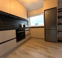 Küche in einer 4-Zimmer-Wohnung mit schwarzen Fliesen und eingebauten Geräten.