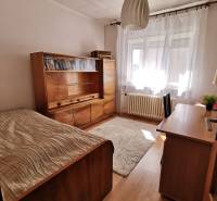 Ein Zimmer in einem Einfamilienhaus mit Holzmöbeln, einem Bett und einem Teppich.