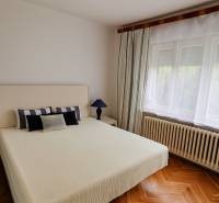 Helles Schlafzimmer im Einfamilienhaus mit Bett, Lampe und Holzboden.
