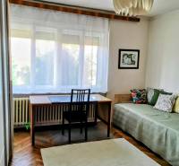 Ein Zimmer in einem Einfamilienhaus mit einem Schreibtisch, einem Bett, einem Teppich und dekorativer Beleuchtung.