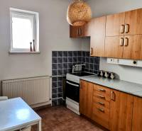 Eine Küche in einem Einfamilienhaus mit Holzschränken, einem Herd und einem weißen Tisch.